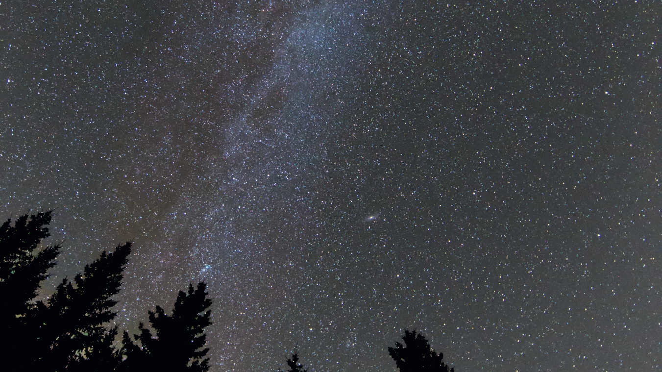 Zdjęcie letniej Drogi Mlecznej unoszącej się nad Schwarzwaldem, wykonane za pomocą pełnoklatkowej lustrzanki Canon 6D z obiektywem 14mm przy f/2,8. ISO 6400, czas naświetlania 20 sek. Fot. U. Dittler